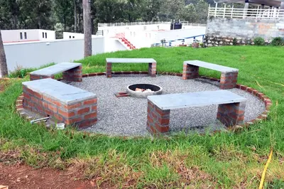 a fire pit with two benches and a fire pitasteryasteryasteryasteryasteryastery at Casa by the hills in Kotagiri
