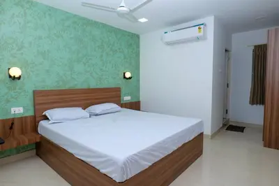 a bedroom with a bed with white sheets and green wallpaper at Balu Residency - A Business Class Hotel in Coimbatore
