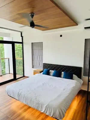 a bedroom with a large white bed with blue pillows at AYD-IN BY GREENLEAVES Resort in Vythiri