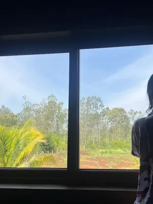 a woman looking out of a window at a field at Jungle flare in Hampāpura