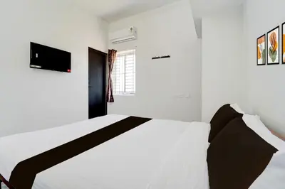 a white bedroom with a bed and a window at Super Hotel O Neelambur Near PSG ITech in Coimbatore