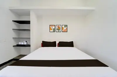 a bedroom with a white bed and shelves at Super Hotel O Neelambur Near PSG ITech in Coimbatore