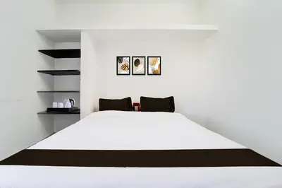 a bedroom with a white bed and black shelves at Super Hotel O Neelambur Near PSG ITech in Coimbatore