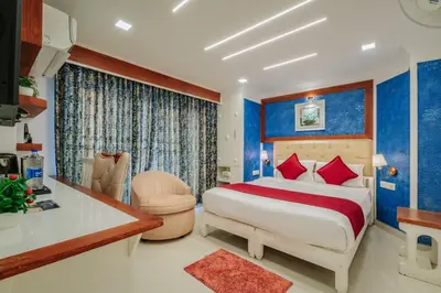a bedroom with blue walls and a bed with a desk at Excellency Airport Hotel in Angamali