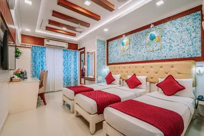 two beds in a hotel room with red pillows at Excellency Airport Hotel in Angamali