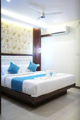 a bedroom with a large white bed with blue pillows at Mysore Elite in Mysore
