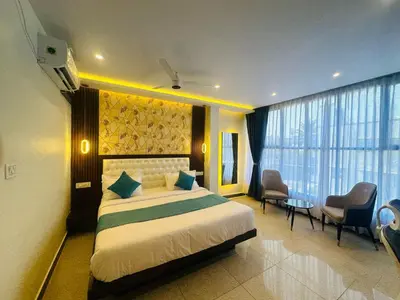 a bedroom with a large bed and a room with chairs at Mysore Elite in Mysore