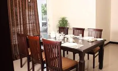 a dining room with a wooden table and chairs at Horizon Heights Apartment in Coimbatore