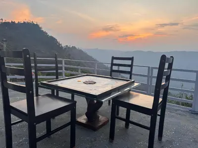 a table and chairs with a view of the water at The Plum Castle in Kodaikānāl