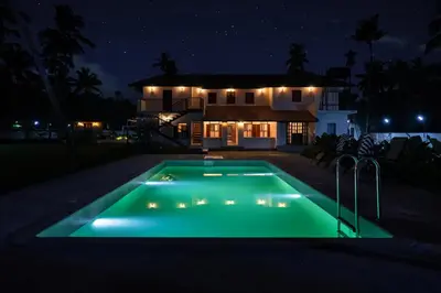 a pool in front of a house at night at Reverie in North Paravur