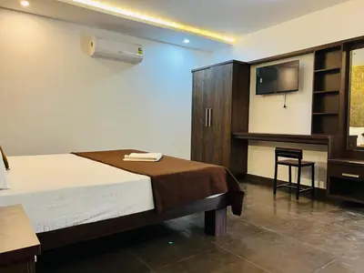a bedroom with a bed and a flat screen tv at 2 Empire One Bedroom with Common Pool in Wayanad