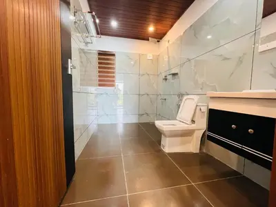 a bathroom with a white toilet and a shower at 2 Empire One Bedroom with Common Pool in Wayanad
