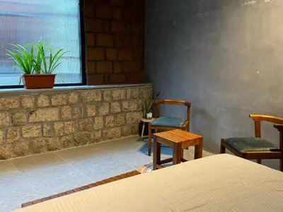 a room with two chairs and a bed and a window at Rustic Nestle, Tirupur in Tiruppūr