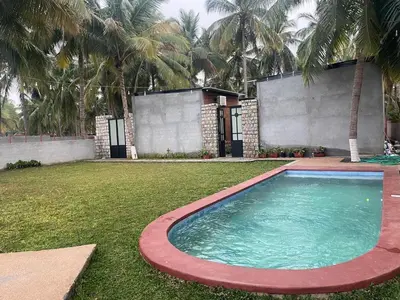 a large swimming pool in a yard with palm trees at Rustic Nestle, Tirupur in Tiruppūr