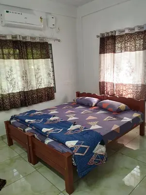 a bedroom with a bed and two windows with curtains at Thrikarthika appartments in Guruvāyūr