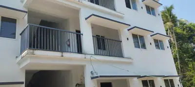 a white building with a balcony and palm trees at Thrikarthika appartments in Guruvāyūr