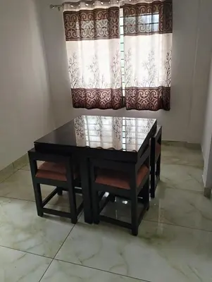 a dining room table with chairs and a window at Thrikarthika appartments in Guruvāyūr