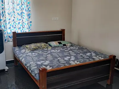 a bedroom with a bed with a wooden frame at Bandipur Jaguar Homestay in Bandipūr