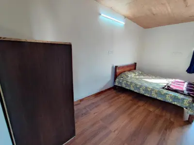 a small room with a bed and a wooden door at Bandipur Jaguar Homestay in Bandipūr