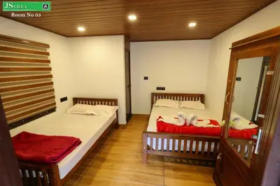two beds in a room with wooden floors at JS homes vattavada in Vattavada