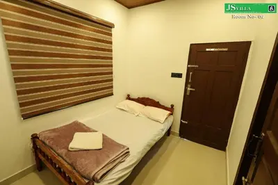 a small bedroom with a bed and a window at JS homes vattavada in Vattavada