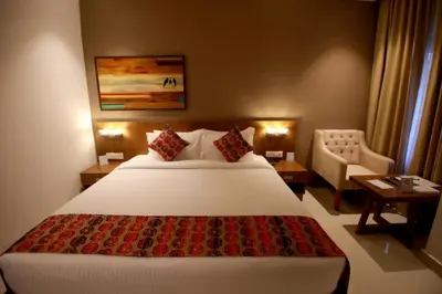 a hotel room with a large white bed and a chair at Ambal Regency in Pudukād