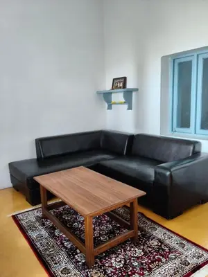 a living room with a black leather couch and a coffee table at Estate Bungalow with Waterfall, Mountain & Valley Views in Kotagiri