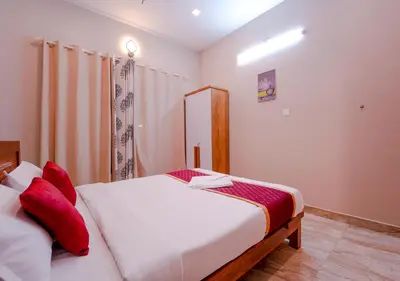 a bedroom with a bed with white sheets and red pillows at Oasis Apartment with Pool in Vythiri in Vythiri