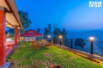 a patio with chairs and a table on a balcony at StayVista at Valley Whispers with BBQ & Bonfire in Ooty