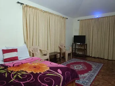 a bedroom with a bed and chairs and a television at Vi stays in Ooty