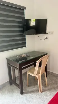 a desk with a chair and a table and a monitor at Portico Resorts in Pandalūr