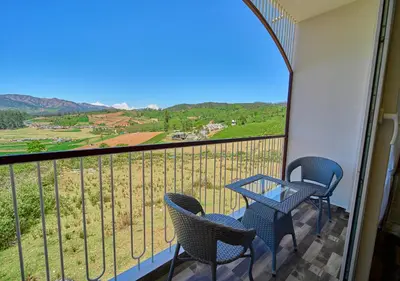 a balcony with chairs and a table and a view at Vihani's Western Clouds Ooty by VOYE HOMES - Peaceful Getaway Near Avalanche Emerald Lake in Ooty
