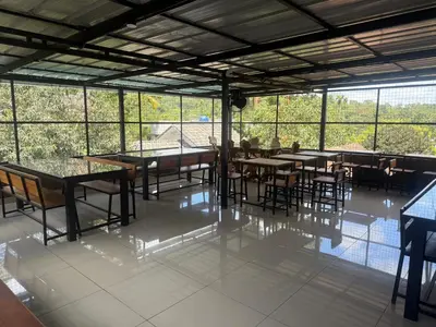 a dining room with tables and chairs and windows at 3 Empire One Bedroom with Common Pool in Wayanad