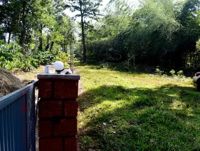 a brick fence with a field of grass and trees at Green Heaven Kuruva Wayanad in Chekadi