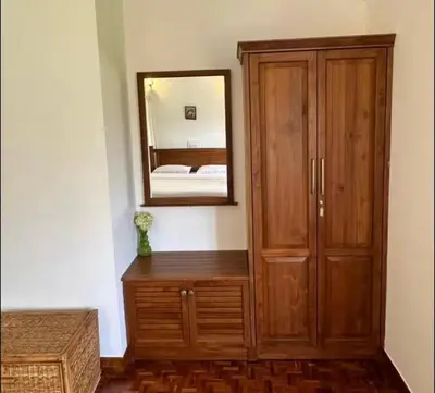 a bedroom with a wooden cabinet and a mirror at Ivy Cottage Kodaikanal in Kodaikānāl