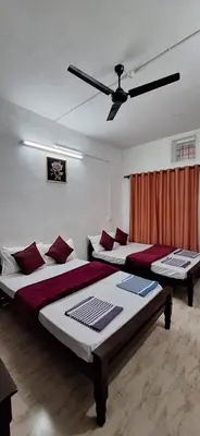 a bedroom with two beds and a ceiling fan at Holiday Apartments & Homestay in Sultan Bathery