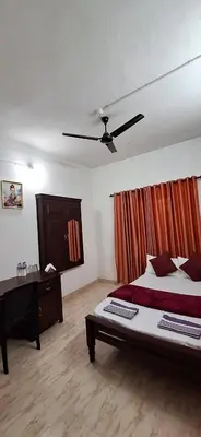 a bedroom with a bed and a desk in it at Holiday Apartments & Homestay in Sultan Bathery