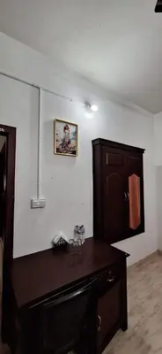 a room with a wooden desk and a cabinet at Holiday Apartments & Homestay in Sultan Bathery