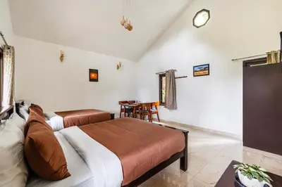 a bedroom with two beds and a table and a clock at Interlaken - 4 BR VIlla in Yedapalli