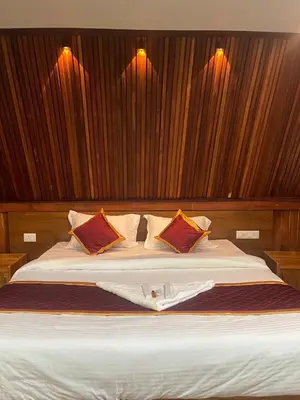 a bedroom with a large white bed with red pillows at River Valley Huts, Wayanad in Panamaram