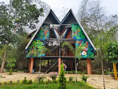 a house with a mural on the front of it at River Valley Huts, Wayanad in Panamaram