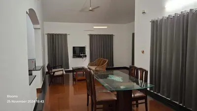 a living room with a glass table and chairs at Stone Villa in Blooms Green Farm in Wayanad