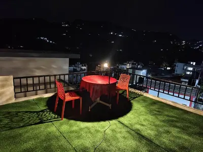 a red table and chairs on a balcony at night at Jazz&Hill in Kodaikānāl