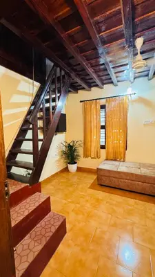 a living room with a staircase and a couch at Pragathi Homestay in Mananthavady
