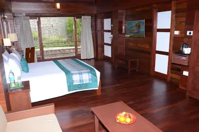 a bedroom with a bed and a table in a room at GReaT Trails Kodaikanal by GRT Hotels in Kodaikānāl