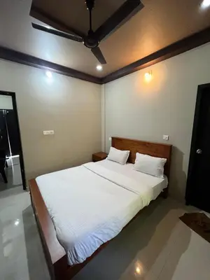 a bedroom with a large bed with white sheets at Kosher Livings Holiday in Kalpetta