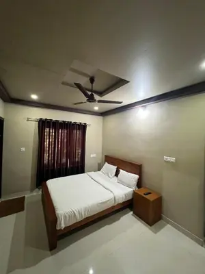 a bedroom with a bed and a ceiling fan at Kosher Livings Holiday in Kalpetta