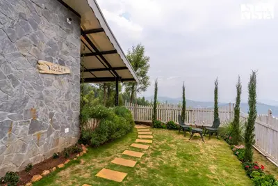 a garden with two benches and a stone wall at StayVista at Under the Stars Lovedale ooty in Ooty