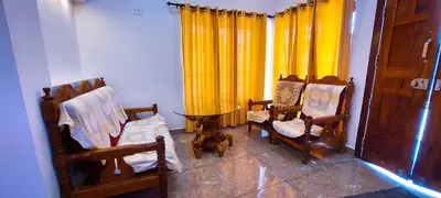a room with chairs and a table and yellow curtains at Sands Villa Homestay in Wayanad