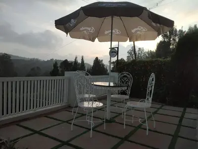 a table and chairs and an umbrella on a patio at FN's Eternia in Ooty